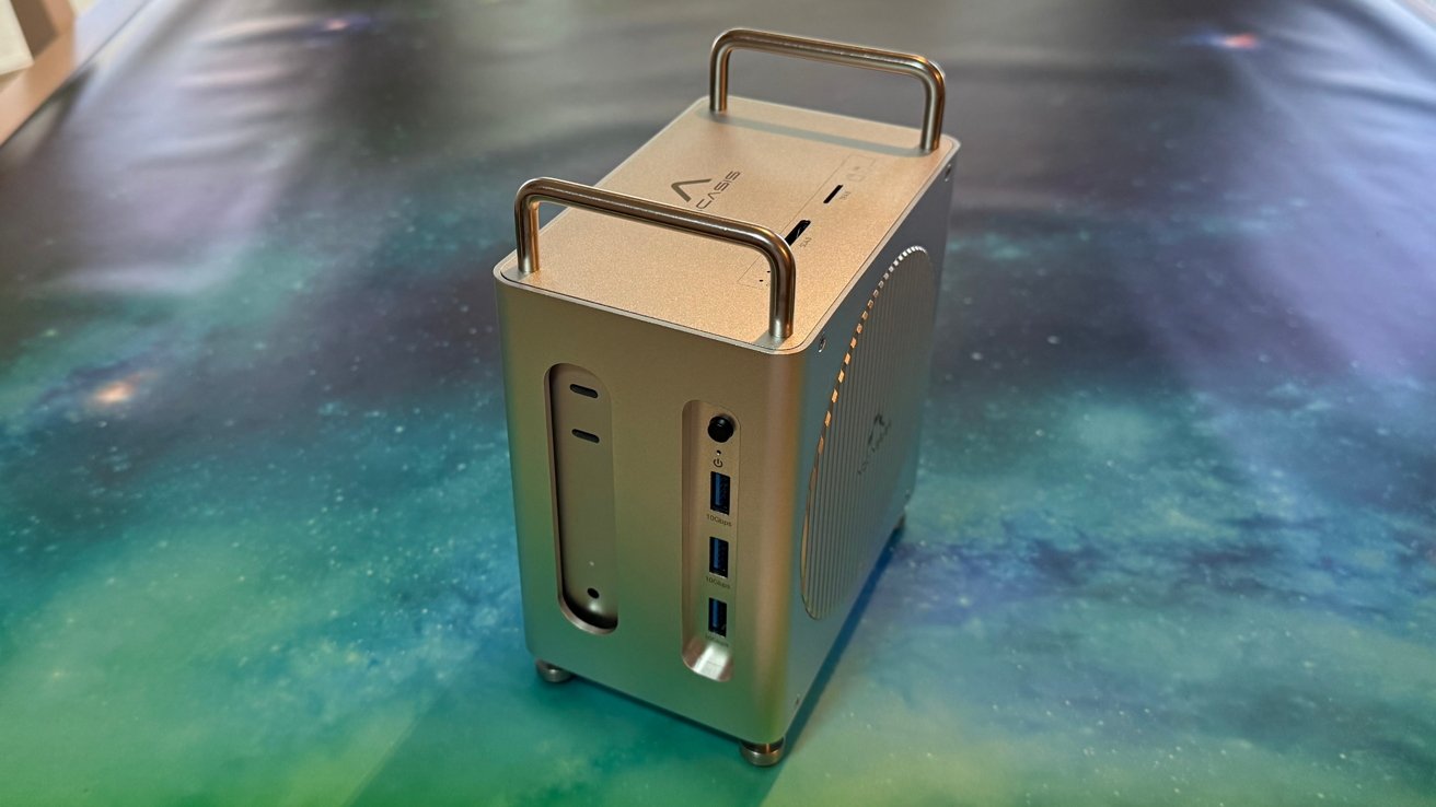 Small metallic computer tower with USB ports and handles on top sits on a starry blue-green background.